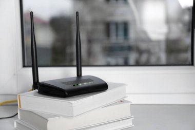 Modern Wi-Fi yönlendirici, pencerenin yanındaki kitap yığınının üzerinde. Metin için boşluk