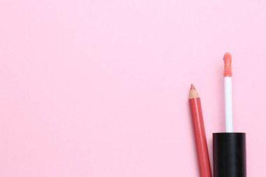 Pembe arka planda parlak dudak kalemi ve sıvı ruj fırçası, metin için yeri olan düz bir yer. Kozmetik ürünleri