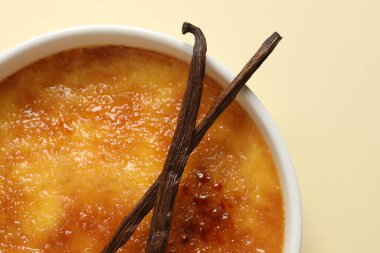 Bej arka planda vanilya çubuklu leziz creme brulee, üst manzara
