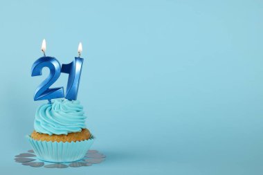 Açık mavi arkaplanda numara şekilli mumları olan enfes bir kek. Mesaj için yer var. Reşit olma partisi - 21. yaş günü