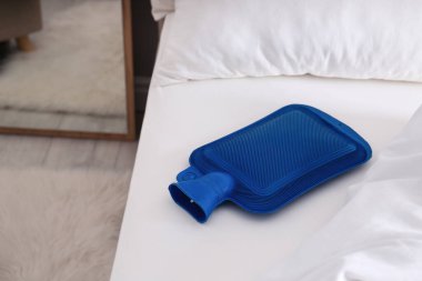 Beyaz yataktaki mavi sıcak su şişesi.