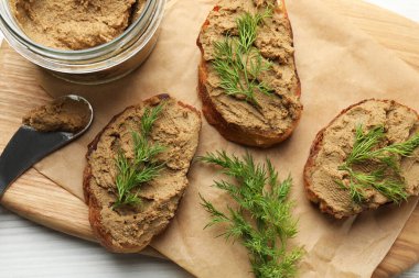 Lezzetli ezmeli ekmek dilimleri ve beyaz ahşap masadaki dereotlar.
