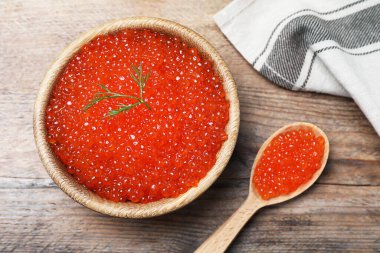 Tahta masada lezzetli kırmızı havyarlı kase ve kaşık, düz yatıyordu.