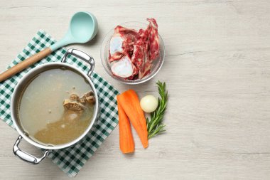 Lezzetli ev yapımı kemik suyu ve beyaz ahşap masa üzerindeki malzemeler, düz yatak. Metin için boşluk