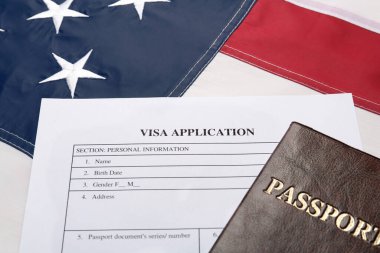Amerikan bayrağında vize başvuru formu ve pasaport, yakın plan.