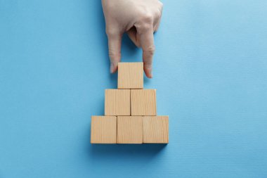 Açık mavi arka planda boş tahta küpleri düzenleyen bir kadın. Metin için boşluk