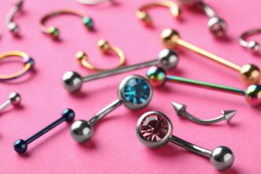 Pembe arka planda piercing takıları, yakın plan.