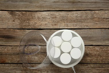 Ahşap masasında kavanozları olan modern yoğurt imalatçısı. Metin için boşluk