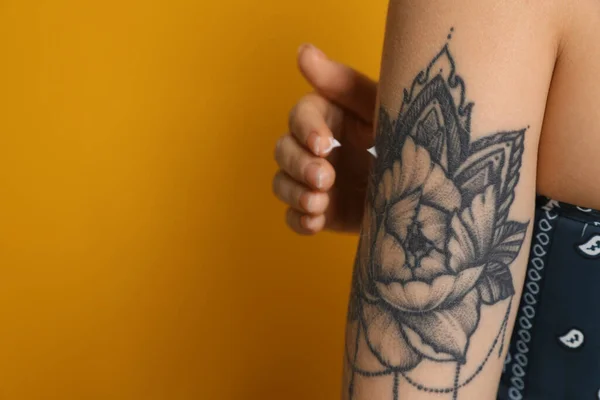 Mulher Aplicando Creme Seu Braço Com Tatuagem Fundo Amarelo Close — Fotografia de Stock