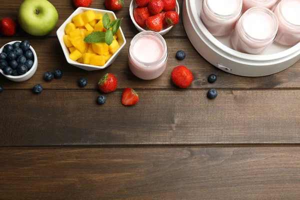木製のテーブル フラットレイアウト上の完全な瓶や異なる果物と現代のヨーグルトメーカー テキストのスペース — ストック写真