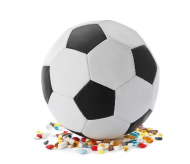 Futbol topu ve beyaz arka planda bir sürü farklı hap. Doping kavramı