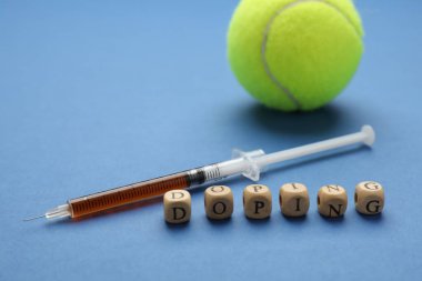 Mavi arka planda kelime Doping, şırınga ve tenis topu ile ahşap küpleri