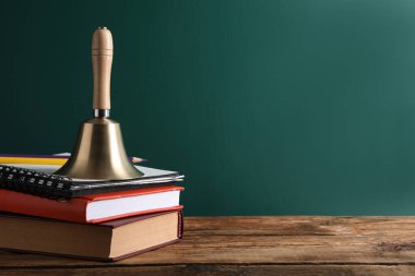 Altın çan, kitaplar ve kalemler yeşil karatahtanın yanındaki ahşap masada, yazı için yer var. Okul günleri