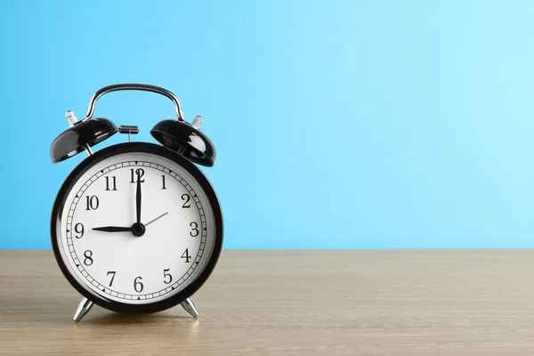 Reloj Despertador Negro Sobre Mesa Madera Sobre Fondo Azul Claro —  Fotos de Stock