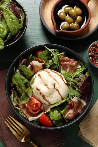 Yeşil ahşap masada servis edilen nefis burrata salatası.