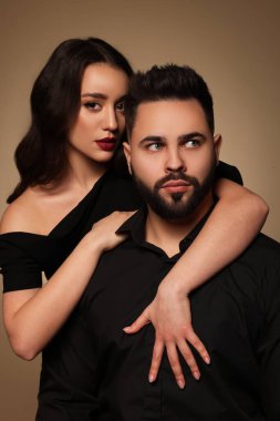 Açık kahverengi arka planda seksi bayan olan yakışıklı sakallı adam.