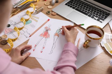 Moda tasarımcısı ahşap masada resim çiziyor, yakın plan.