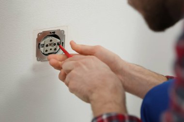 Tornavidalı elektrikçi prizi tamir ediyor, yakın plan.