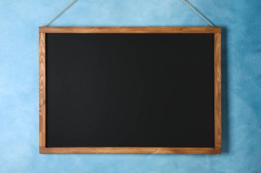 Açık mavi duvarda asılı temiz siyah karatahta
