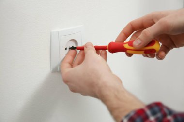 Tornavidalı elektrikçi prizi tamir ediyor, yakın plan.