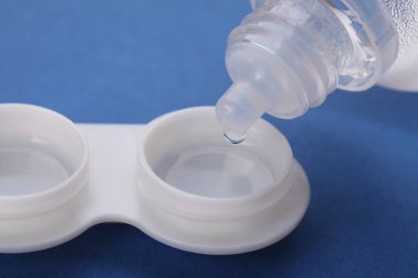Mavi arkaplanda kontak lensleri olan çözelti dosyaya damlatılıyor, yakın plan