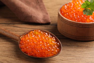 Tahta masada lezzetli kırmızı havyarlı kaşık ve kase, yakın plan.