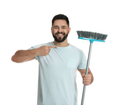 Beyaz arka planda süpürgesi olan genç bir adam.