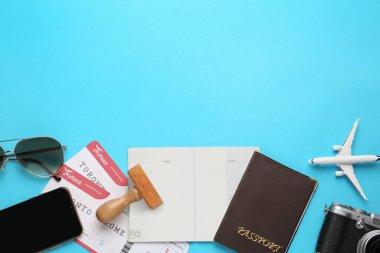 Açık mavi arka planda pasaportlu düz kompozisyon, pul ve uçuş biletleri, metin için boşluk