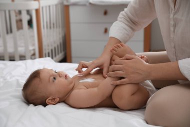 Anne evdeki bebeğine nemlendirici krem sürüyor, yakın plan.