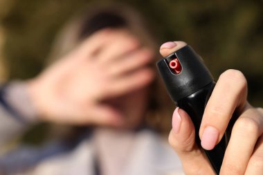 Elle gözlerini kapatan ve dışarıda biber gazı kullanan genç bir kadın, teneke kutuya odaklan.