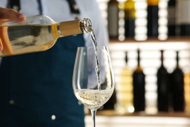 Barmen restoranda bardağa şarap dolduruyor.