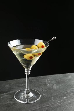 Koyu arka planda gri masada zeytinli martini kokteyli