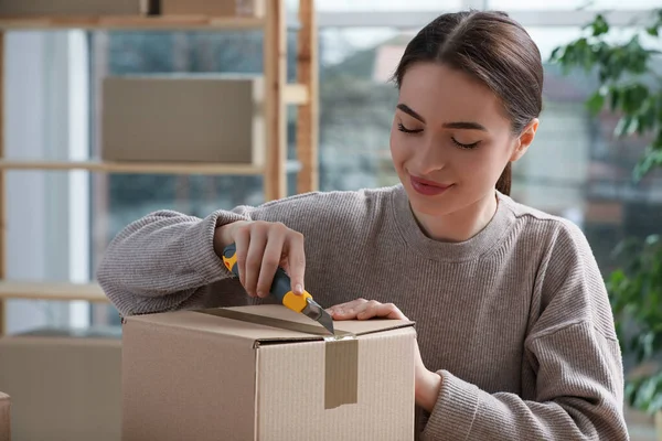 Ung Kvinna Som Använder Verktygskniv För Att Öppna Paket Inomhus — Stockfoto