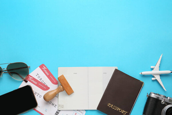 Flat lay composition with passports, stamp and flight tickets on light blue background, space for text