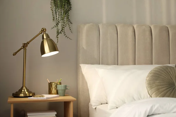 寝室の木製のナイトスタンドでスタイリッシュな黄金のランプと文房具 内装要素 — ストック写真