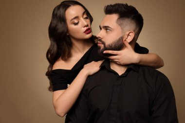 Açık kahverengi arka planda seksi bayan olan yakışıklı sakallı adam.