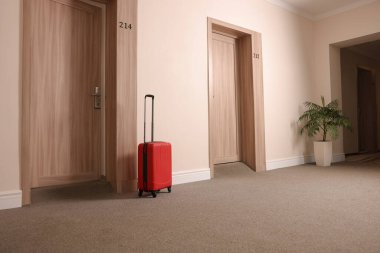 Boş otel koridorunda modern kırmızı bavul.