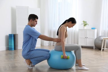 Ortopedist, hastaya klinikte dambılla egzersiz yapmasına yardım ediyor. Skolyoz tedavisi