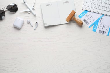 Beyaz ahşap masa üzerinde pasaport, pul ve uçuş biletleri ile düz kompozisyon, metin için boşluk
