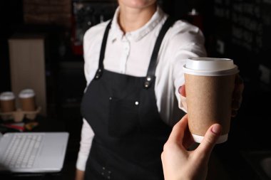 Barista, kahveli paket kâğıt bardağı müşteriye veriyor, yakın plan.