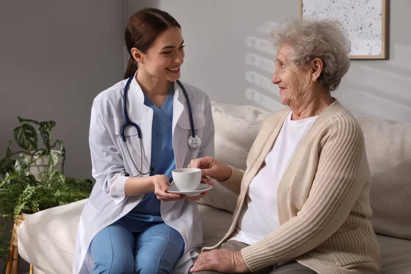 Junge Pflegerin Gibt Seniorin Zimmer Trinken — Stockfoto