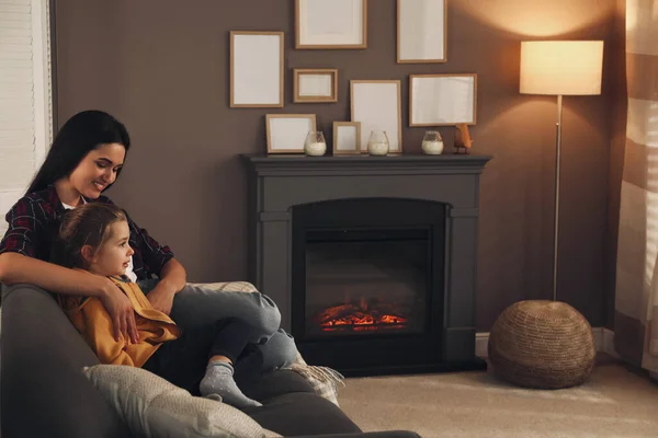 快乐的母亲和女儿在家里壁炉边的沙发上共度时光 案文的篇幅 — 图库照片