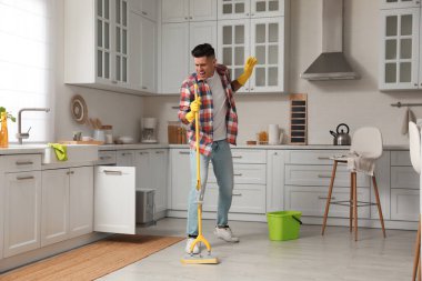 Evde temizlik yaparken paspaslı adam şarkı söylüyor.