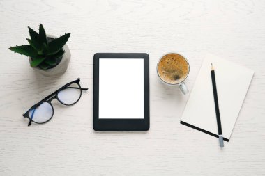 Düz kompozisyon, beyaz ahşap masa üzerinde modern e-kitap okuyucu ile yatıyordu