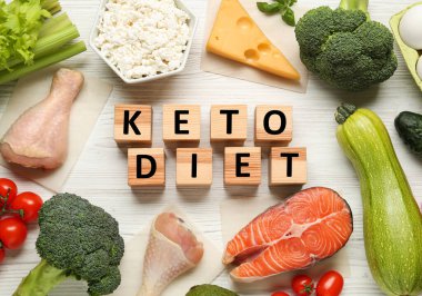 Keto Diyet cümlesinin küpleri ve beyaz ahşap masa üzerinde farklı taze ürünler, düz yatıyordu