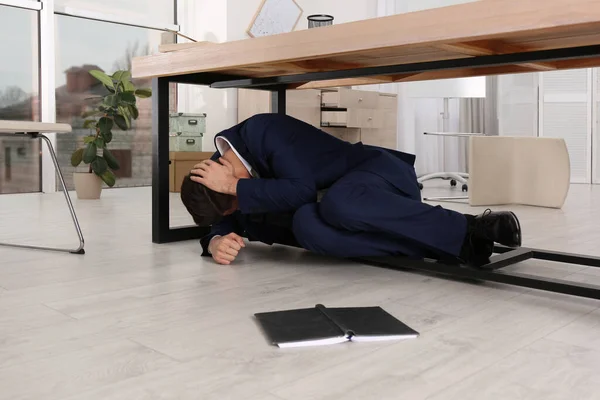 地震時にオフィスの机の下に隠れて怖い男 — ストック写真