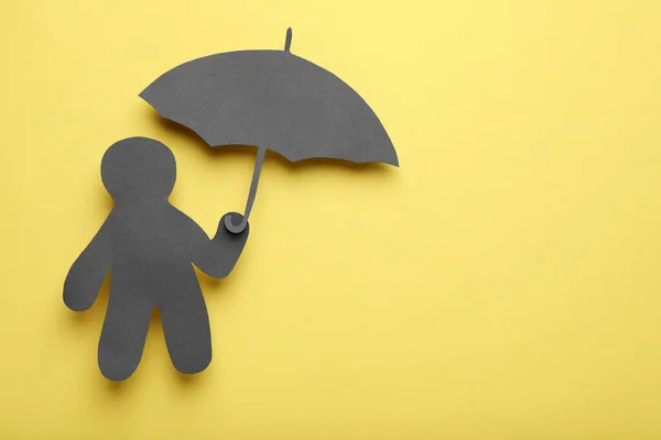 Black Paper Cutout Human Holding Umbrella Yellow Background Top View — Stock Photo, Image