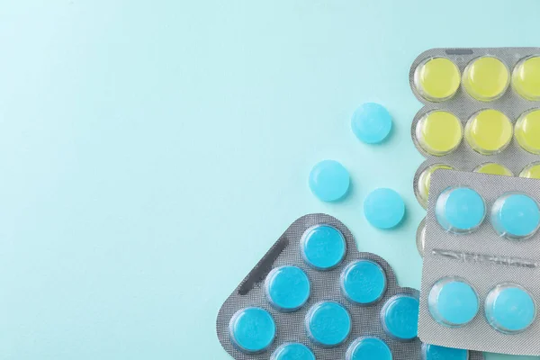 Colorful cough drops on light blue background, flat lay. Space for text