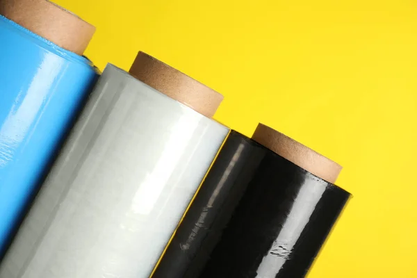 Rolls of different stretch wrap on yellow background, closeup
