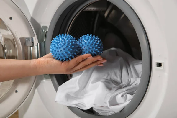 洗濯機に青いドライヤーボールを入れる女 — ストック写真